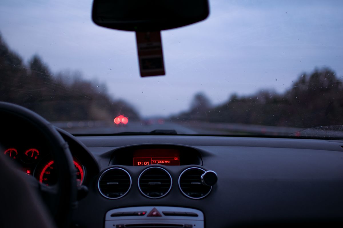 View from a car dashboard looking through the windshield at the road at twilight