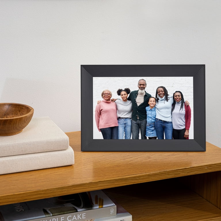 Black digital Wi-Fi photo frame displaying a multigenerational family portrait on a wooden shelf